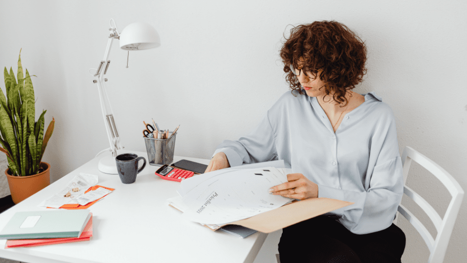 A person sitting at a desk gathering documents for an annual report