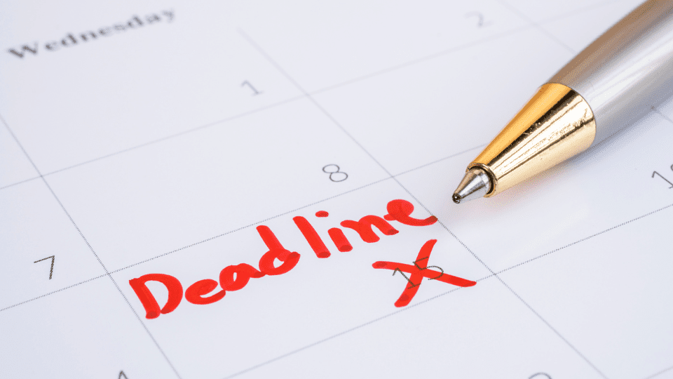 A pen on a calendar with the word "deadline" written on it