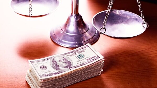 A stack of money and a balance scale on a wooden table
