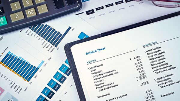 Financial documents on a desk with a calculator and glasses