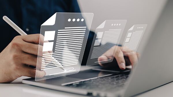 A person working on a laptop with documents on the screen