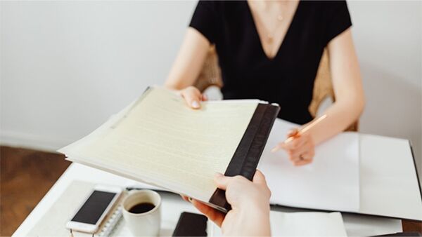 Two people exchanging paperwork at a desk