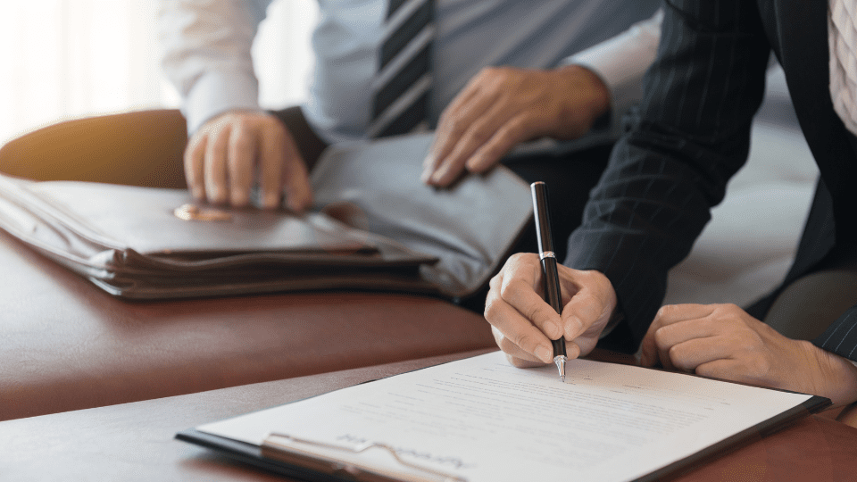 Two people signing documents at a desk