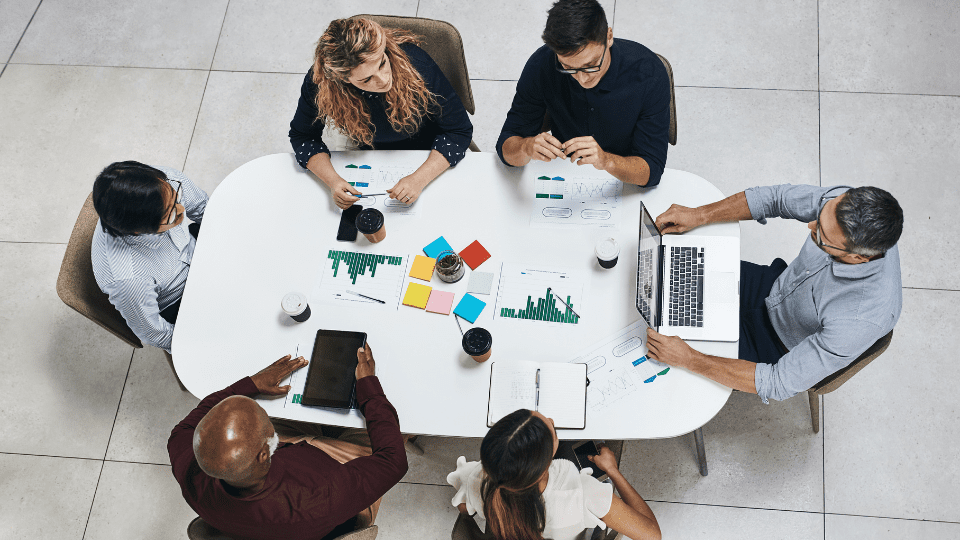 A group of business professionals gathered around a table, discussing and evaluating business structures for mid-market companies
