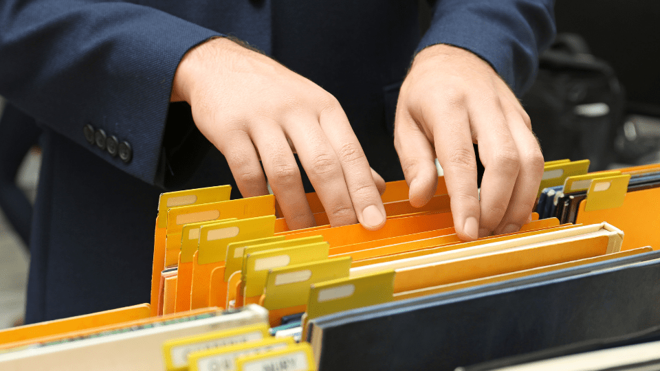 A person in a suit is sifting through a bunch of files