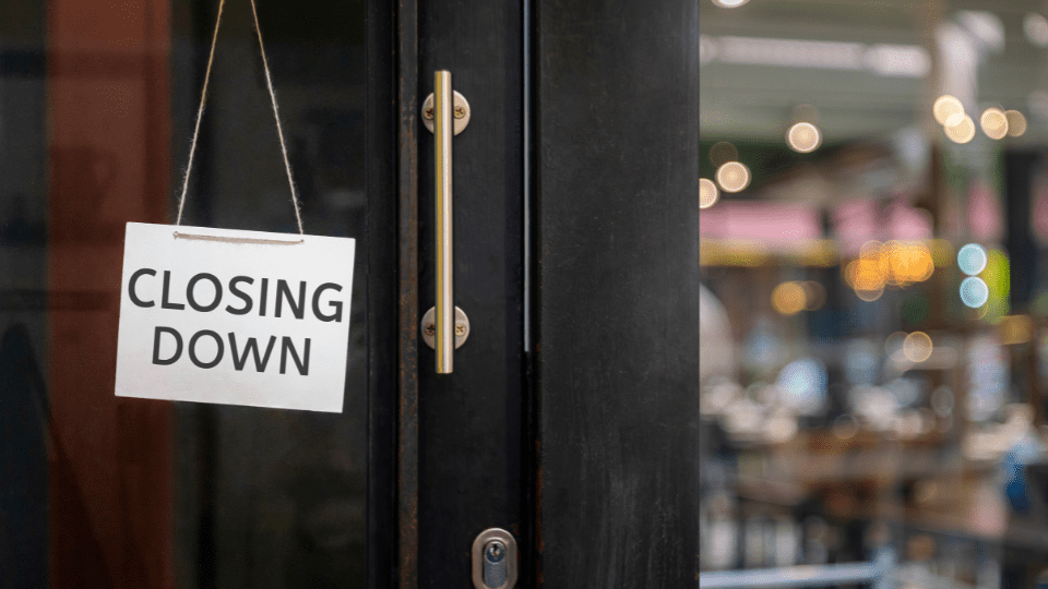 A “Closing down” sign hanging from the door of a business.