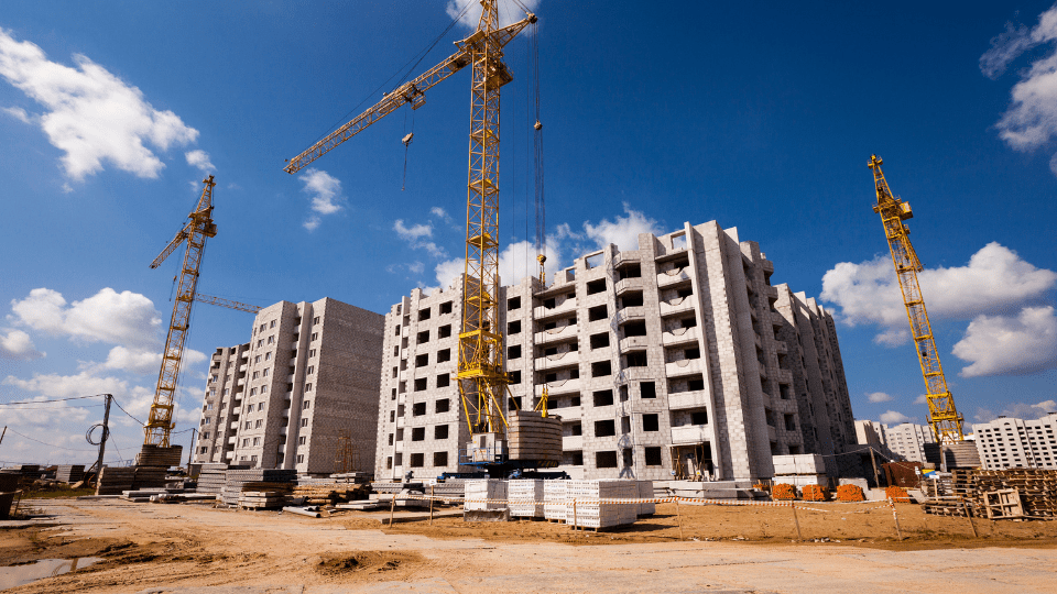 A half-completed building at a construction site with cranes around it.