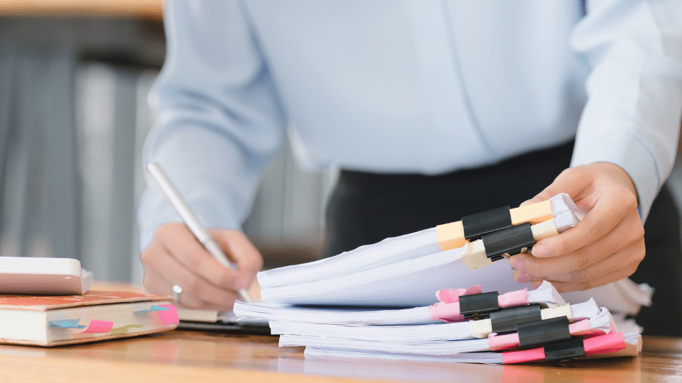 A person in a business suit sorting through various paperwork.